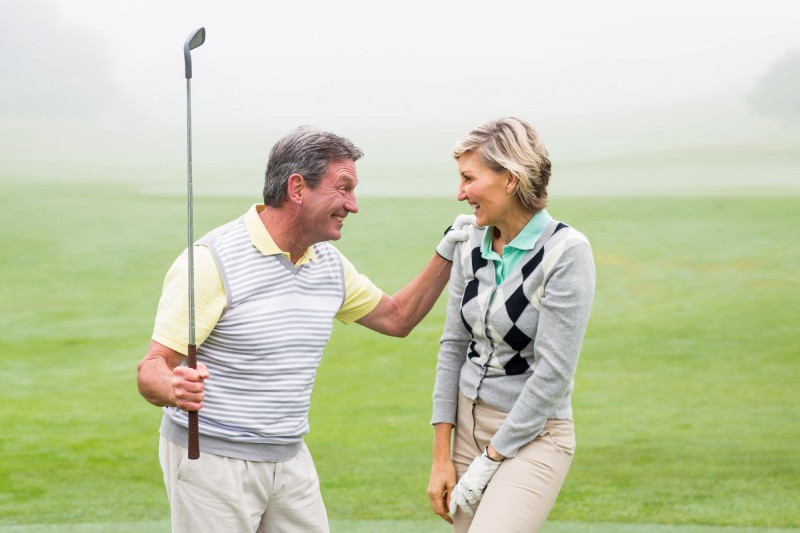 Excited golfing couple cheering on a foggy day at the golf course