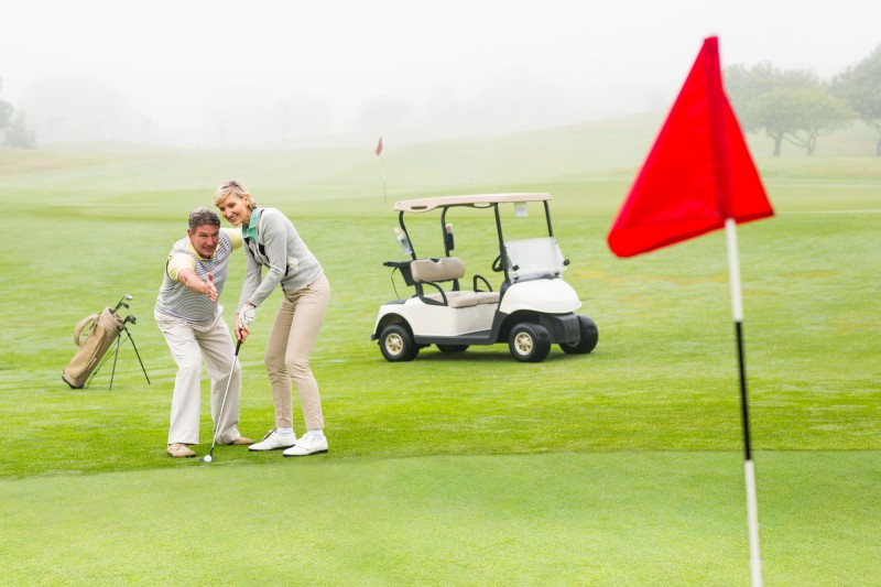 Golfing couple putting ball together on a foggy day at the golf course